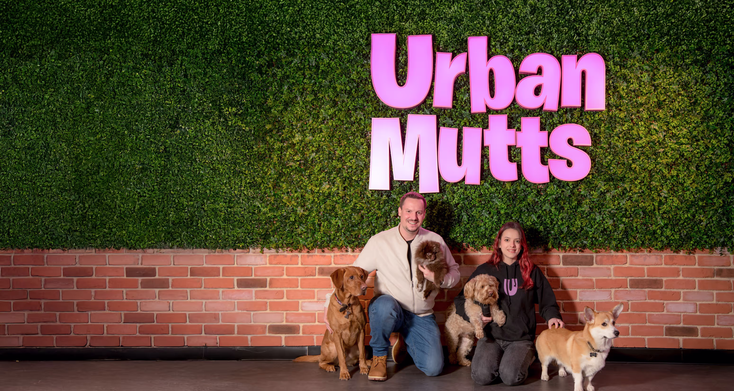 The Urban Mutts team with their dogs by the green wall